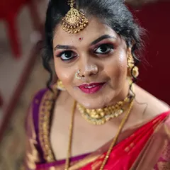 A close-up bridal portrait that focuses on the bride's expressive eyes and beautiful makeup. The rich colors of her red and purple saree are captured vividly.