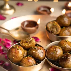 Decadent gulab jamuns made with jaggery, styled for a Diwali-themed shoot with the warm glow of diyas in the background.