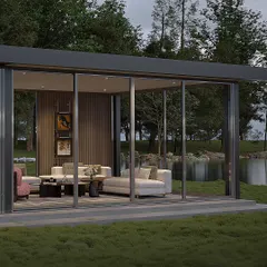 This view shows the glass-enclosed section of the prefab lounge, situated by a lake. The floor-to-ceiling sliding doors allow the space to be opened up to the outdoors or closed for protection from the weather.
