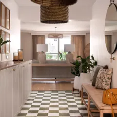 The entryway sets a relaxed yet elegant tone with its green checkered floors, woven bench, and oversized rattan pendant lights. This space immediately draws you into the home's calm, coastal-inspired world.