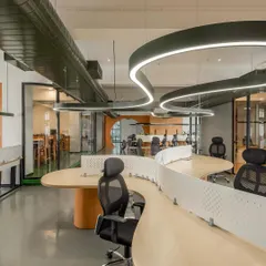 An open-plan office featuring custom serpentine workstations. Working with our fabrication partners, we designed these desks to encourage interaction while maintaining individual space with perforated dividers.
