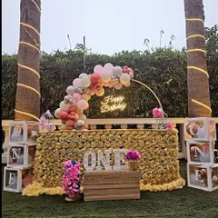 This first birthday setup is all about golden glamour. We designed this stunning outdoor party featuring a table covered in golden roses, a custom balloon arch, a "Happy Birthday" neon sign, and personalized "ONE" photo blocks to celebrate the milestone.