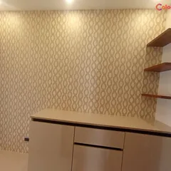 This elegant beaded trellis wallpaper was installed in a foyer area, creating a sophisticated first impression. The geometric pattern and neutral tones work beautifully with the overhead lighting and wooden shelves.