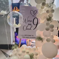 For a modern and dreamy baby shower, I created this "We're on Cloud 9" theme. The decor features an all-white balloon garland with delicate baby's breath flowers and a custom welcome sign on an easel.