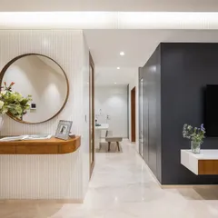 A view from the entrance, showing how the different elements come together. The round mirror softens the lines, and the reflection offers a peek into the dining area, creating a sense of interconnected space.
