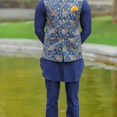 A complete ethnic ensemble featuring a navy blue kurta set with a contrasting blue and gold jacquard Nehru jacket. This is a perfect look for a wedding guest.