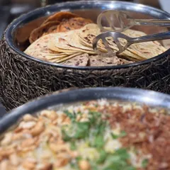 A glimpse of a Diwali buffet spread, featuring a large platter of biryani and a basket of assorted Indian breads.