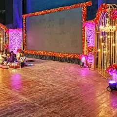 For corporate events and sangeet nights, I build stages that incorporate modern technology. This setup features a large central LED screen framed by floral decor and elegant, illuminated side panels, providing a professional backdrop for performances and presentations.