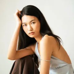 A seated portrait with a relaxed yet direct expression, showcasing a softer, more approachable look.