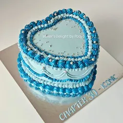 Turning 30 in style with this dreamy vintage-style heart cake. The Lambeth-style piping in shades of blue, accented with silver pearls, creates a chic and timeless look.