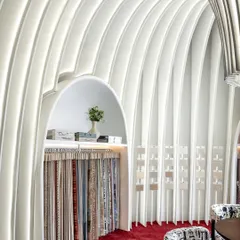 A detail of the curved walls and the integrated display niche. We let the fabric architecture create its own functional spaces, seamlessly blending product display with the overall artistic concept.