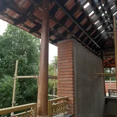 The restoration process in action. Here, a new brick wall is being integrated with the traditional wooden pillar and tiled roof structure, blending old and new materials with care.
