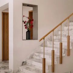 In Cocoon House, we designed the staircase to be more than just a functional element. The combination of white marble, a light wood handrail, and custom brass and wood balusters creates a sculptural feature, while a simple niche with a vase of flowers adds a moment of beauty.