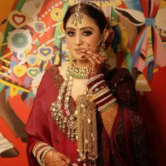A full portrait of my bride, showcasing how the complete look comes together. The makeup, with its defined eyes and balanced tones, harmonizes perfectly with her maroon outfit and the intricate details of her jewellery.