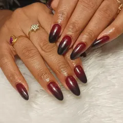 A bold and beautiful ombre design, blending from a deep red at the cuticle to black at the tip on long, almond-shaped extensions.