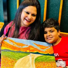 A mother and son duo proudly displaying their collaborative landscape painting. Textured art is a fantastic way for families to create a joint masterpiece.