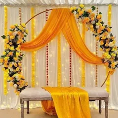 A simple metal ring can be transformed into an elegant and contemporary photo booth or backdrop. I decorated this one with asymmetrical floral arrangements and a flowing yellow drape for a light, airy feel.