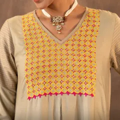 A closer look at the vibrant Pakka hand embroidery on our Ruhani Sage Green Kurta. The dense, geometric stitches, accented with mirrors and pops of pink, frame the neckline and showcase the incredible skill of our desert artisans.