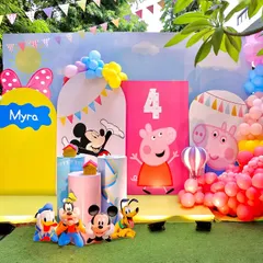 A vibrant outdoor party setup combining the worlds of Peppa Pig and Mickey Mouse. The colorful backdrops, character cutouts, and playful balloon decorations create a fun-filled atmosphere for a fourth birthday.