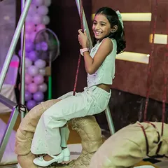 A happy girl enjoying a tire swing, part of our custom-built indoor obstacle course. It's all about creating unique and playful experiences.