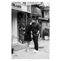 A timeless black and white photo of a couple sharing a quiet moment on a city street. It shows that even in a busy urban setting, we can find and capture intimate connections.
