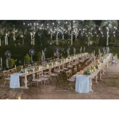 The full setup for an elegant outdoor reception dinner. The long, parallel tables create a sense of community, while the string lights and palm trees add a touch of tropical romance.