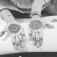 This black and white photo highlights the clean lines of a simple mandala design. Paired with leafy motifs on the fingers, it's a beautiful and understated choice.