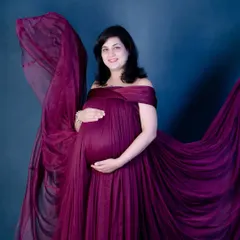 Another angle from our fabric toss session. The flowing train of the gown adds a sense of movement and grandeur to this elegant studio maternity shot.