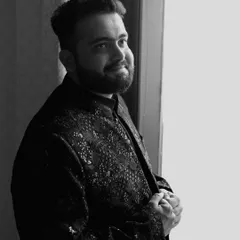 A classic black and white portrait of the groom looking out a window, capturing a quiet, contemplative moment.