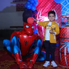 A close up of the birthday boy with a large Spiderman foil balloon. We use a mix of props and balloons to add depth and fun to our themed birthday decorations.