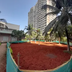 A wide view of the prepared site, with the red soil evenly spread and enclosed by a green net to protect the area.