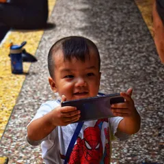 A happy toddler sharing a moment with his grandmother over a phone. This candid photo captures a slice of modern life and the simple, joyful connections between generations.