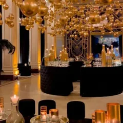 We transform venues to bring any theme to life. For this Golden Jubilee celebration, we created a luxurious atmosphere with a ceiling of suspended golden orbs and elegant black and gold decor.