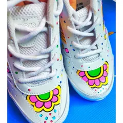 A front view of the sneakers, highlighting the symmetrical floral design on the toe box, complemented by colorful dots.