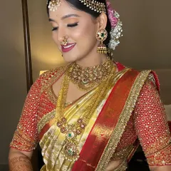 A close-up of this stunning bride, showcasing the harmony between her gold and red Kanjeevaram saree, the intricate temple jewellery, and the classic makeup look with a defined eye and a joyful, bold lip.