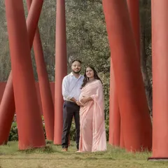 A unique outdoor shot using modern red pillars as a framing device for this couple's portrait in a pink saree.
