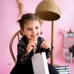A smile that shines brighter than any diamond! This little girl is enjoying her glam-themed photoshoot, complete with shopping bags and a big happy grin.