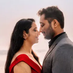 A close-up, intimate portrait with the soft, hazy light of the Mumbai shoreline in the background. The focus is entirely on the couple's connection and the romantic atmosphere.