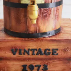 The base of the barrel cake was designed to look like a rustic wooden crate, complete with a "Vintage 1973" inscription.