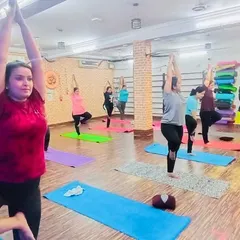 Our instructor guiding the class through a balancing posture. We provide hands-on guidance to help everyone, especially beginners, feel confident.