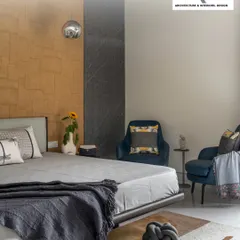 Texture and color come together in this cozy bedroom. The combination of a stone-textured accent wall, a comfortable bed, and plush armchairs creates a perfect corner for unwinding after a long day.