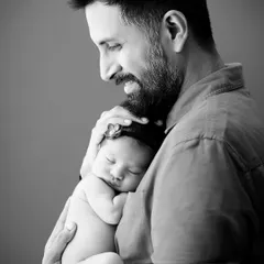 Sometimes, the most powerful emotions are captured without color. This black and white portrait of a father holding his newborn close emphasizes the profound connection and tenderness of their first moments together, a key feature of our moody portrait sessions.