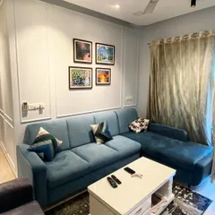 In this project, a comfortable teal L-shaped sofa is set against a wall with classic molding, adding a layer of texture and sophistication. This shows how I blend contemporary furniture with timeless architectural details for a richer look.