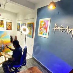 Here I am at work in my studio, focused on a large canvas. The blue wall with my logo is the heart of my creative space.
