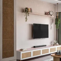 This TV unit combines a textured wall with a low-profile console featuring rattan cabinet doors. The design is clean and modern, with a floating shelf for displaying personal decor items.