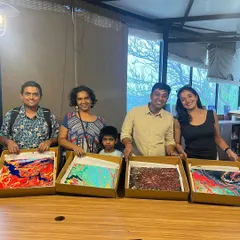 A happy group showing off their finished fluid art pieces. The vibrant colors and abstract patterns make for some seriously cool art.