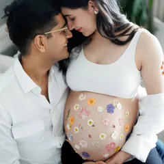 Holding their whole world between them. This intimate portrait with her belly adorned with fresh, colorful flowers is a beautiful and creative representation of the life and love they are growing.