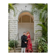 A picture of perfect partnership. The couple stands together, framed by a beautiful archway and lush greenery, creating a classic and elegant wedding portrait that symbolizes their new beginning.