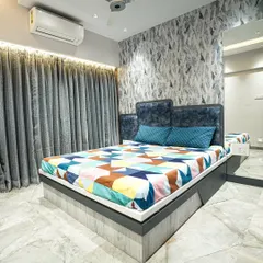 For this boy's bedroom, I used a calming blue color palette. The design includes a custom bed, a feature wall with abstract wallpaper, and mirrored panels to make the room feel more spacious.