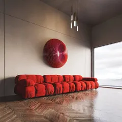 This view of the red abstract sculpture shows it in a room with a large window, highlighting how natural light interacts with its three-dimensional fins.